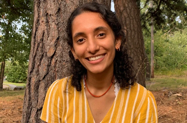 Smiling PA student wearing a striped yellow shirt, posing by a tree.